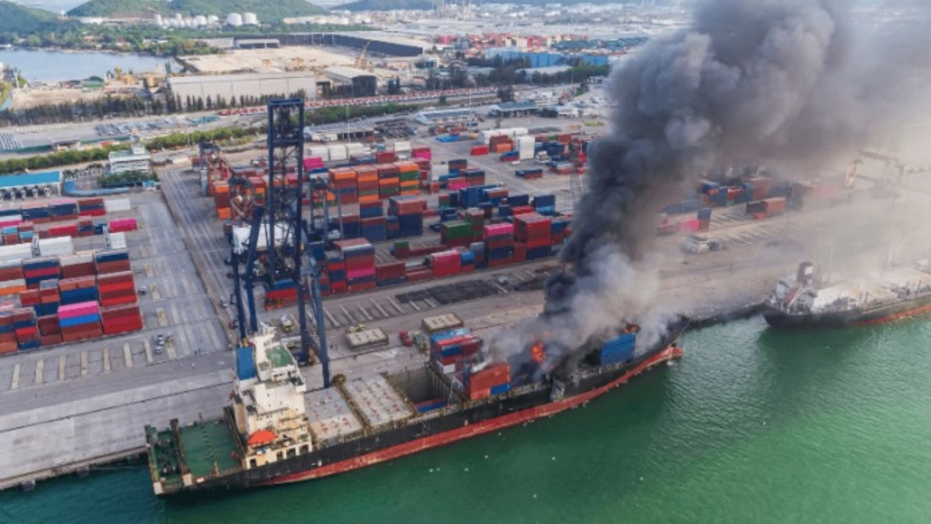 Buque portacontenedores en llamas atracado en terminal portuaria - Vista aérea de incendio marítimo requiere determinación de origen y causas